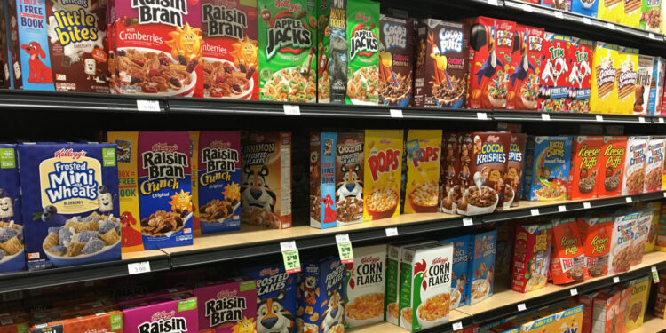 Grocery store shelves, filled with colorful cereals, like Raisin Bran, Apple Jacks, Pops, and Froot Loops.